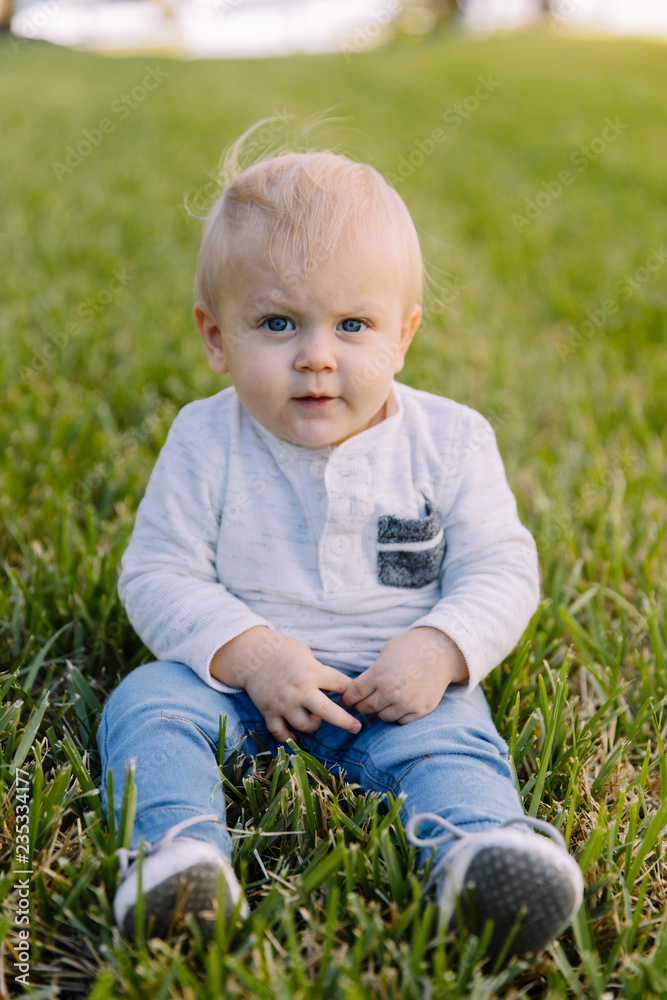 Cute and Adorable Young Toddler Baby Boy Playing in the Backyard Green Grass and Smiling at the Camera Cute and Adorable Young Toddler Baby Boy Playing in the Backyard Green Grass and Smiling at the Camera