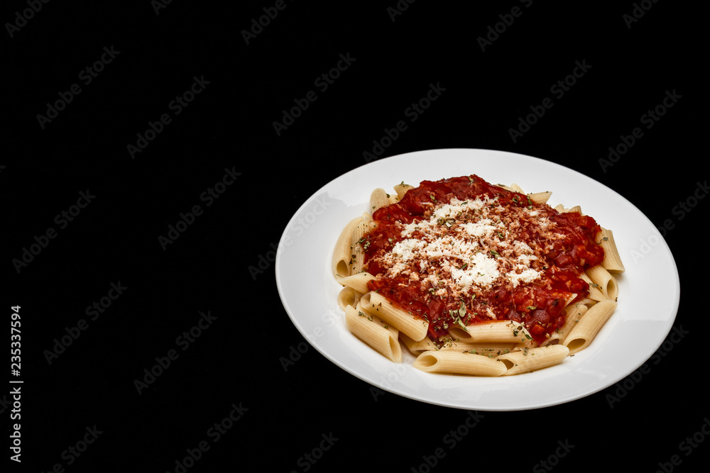 penne meal with red sauce and grated cheese, black background penne meal with red sauce and grated cheese, black background