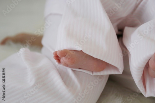 tender bare feet of a newborn baby in pink pajamas in a happy childhood