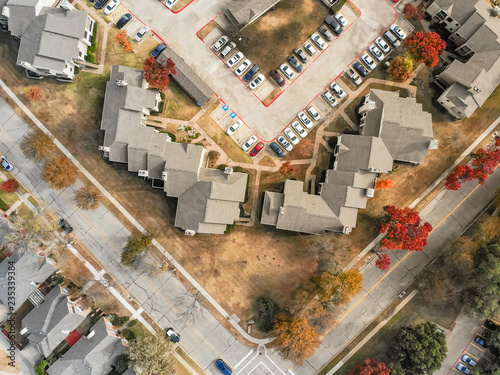 Beautiful aerial view of apartment complex near local street with sidewalk surrounded by colorful autumn leaves. Flyover rental housing subdivided unit flats near Dallas, Texas, USA photo