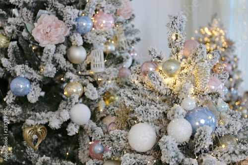 elegant beautiful new year and Cristmas tree with white, pink and blue toys under the instant snow 