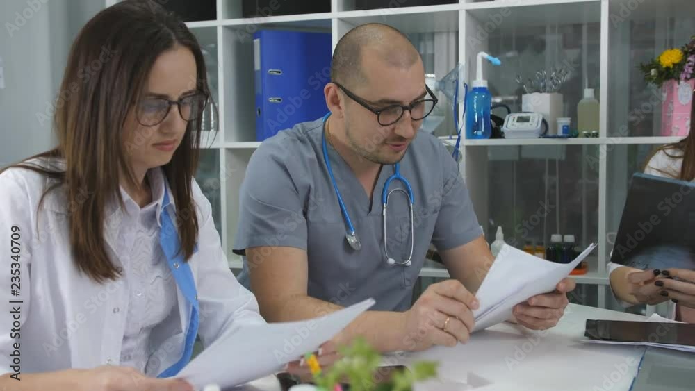 Team of doctors having a meeting in the office. Three doctors at the Desk in the office of counsel. Team of doctors having a meeting in the office. Three doctors at the Desk in the office of counsel.