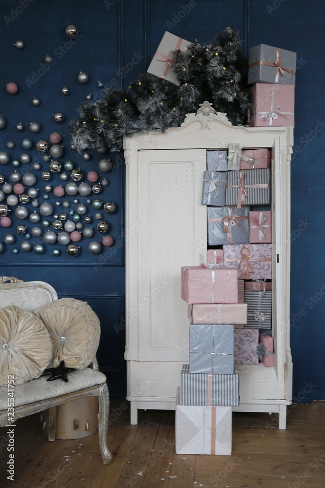 Pink and silver Christmas balls against a dark blue wall next to the white wardrobe with white and pink gifts. hello winter December,  January and February