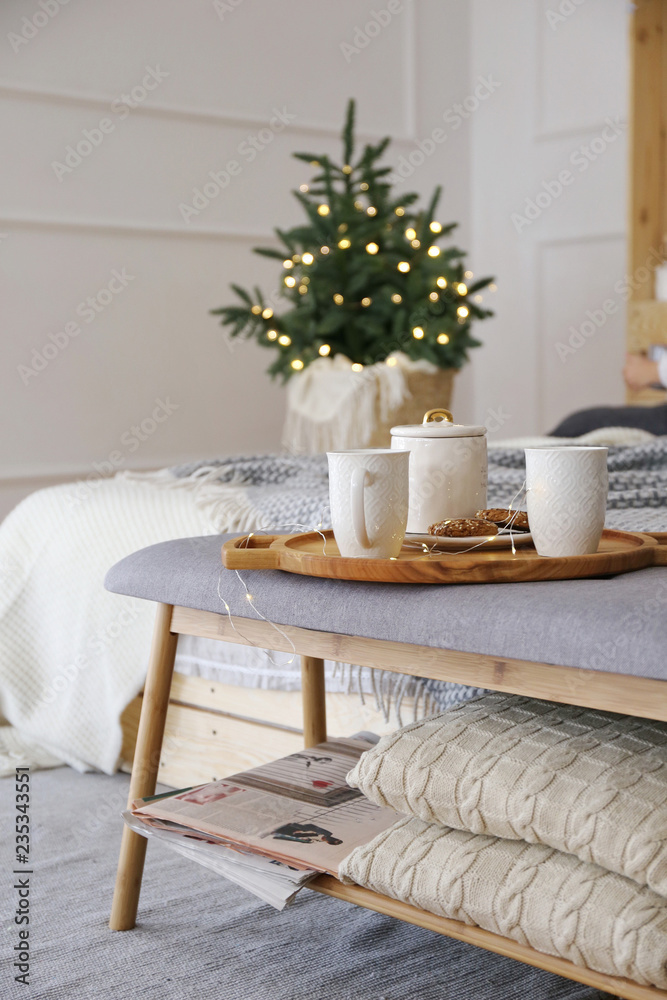 Christmas tree in a wicker basket on a wooden floor in the bedroom  of the luxury apartment. Hello Winter, December, January and February. Huge-style Christmas Decorated Apartments