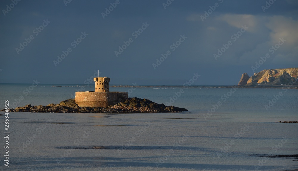 St Ouen's Bay, Jersey, U.K.
Telephoto image of the 18th century military tower in the bay at high tide under dramatic stormy cloud cover in Autumn being lit by the last sunshine of the day.