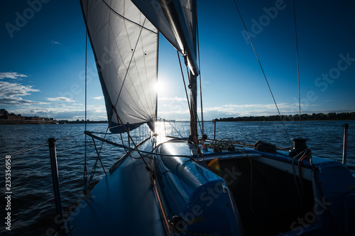 View from the deck to the bow of a sail yacht tilted in a wind on a sunset