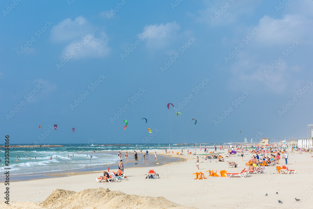 Tel Aviv, Israel - Oct 25th 2018 - Big group of people enjoying a sunny day in a beach with many kites in the air in Israel
