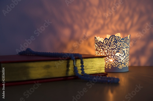 Quran and rosary beads on the white background with light lantern or candle for Islamic concept. Holy book Koran for Muslims holiday, Ramadan,blessed Friday message and three months