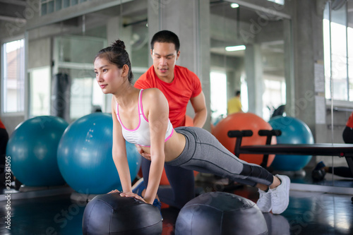 Attractive sports people are working out with fitness balls in gym