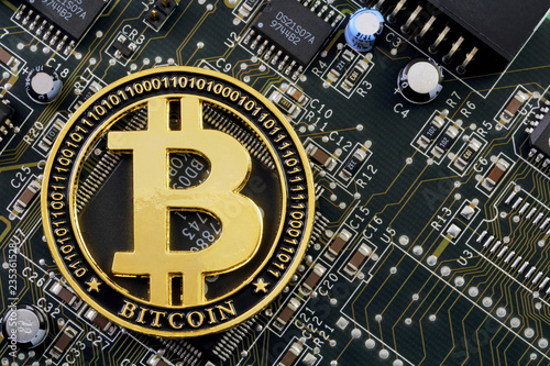 Golden bitcoin cryptocurrency on computer electronic circuit board. Cybercrime background