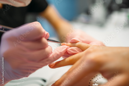 Beautician applying nail varnish to female client