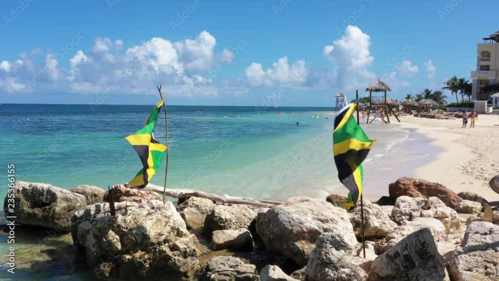 Aerial footage of jamaican flags on a beautiful tropical caribbean beach on Jamaica
