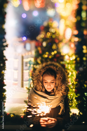 Woman in warm clothing holding sparkler