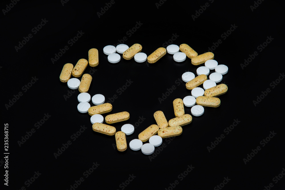 heart shaped pills on a black background heart shaped pills on a black background