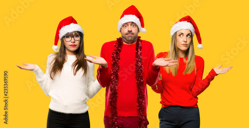 A group of people Girl with celebrating the christmas holidays having doubts and with confuse face expression on yellow background