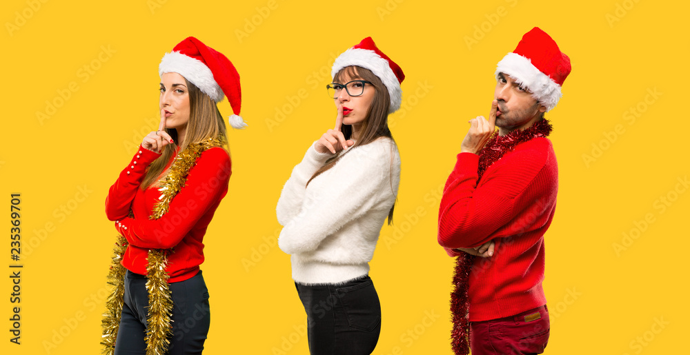 Fototapeta premium A group of people Blonde woman dressed up for christmas holidays showing a sign of closing mouth and silence gesture on yellow background