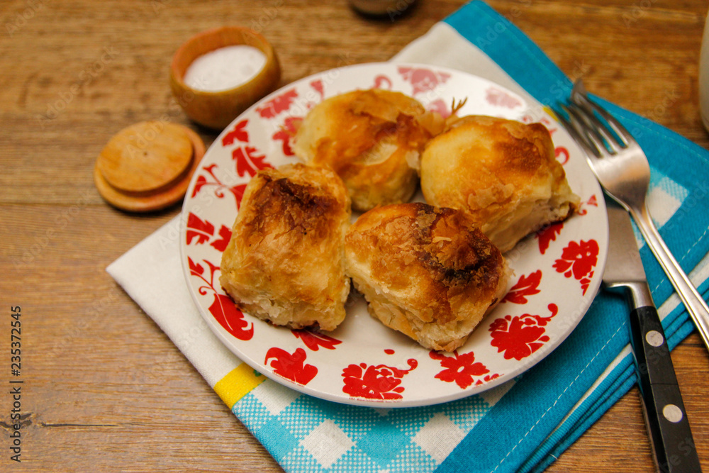 Traditional Bosnian pastry- manti borek with cheese on wooden table with yogurt. rustic background with low light and old bowls. Traditional Bosnian pastry- manti borek with cheese on wooden table with yogurt. rustic background with low light and old bowls.