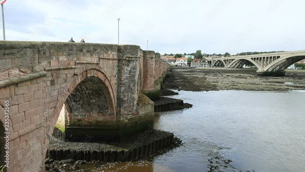 Berwick Upon Tweed old bridge couple walk. Northernmost town in England at the mouth of the River Tweed. An Anglo Saxon settlement from 10th century. Traditional market town. Berwick Upon Tweed old bridge couple walk. Northernmost town in England at the mouth of the River Tweed. An Anglo Saxon settlement from 10th century. Traditional market town.