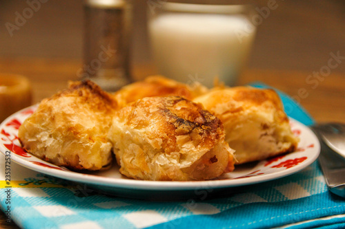 Traditional Bosnian pastry- manti borek with cheese on wooden table with yogurt. rustic background with low light and old bowls.