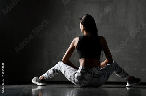 Young sporty woman after gymnastics stretching fitness exercises workout sitting on floor 