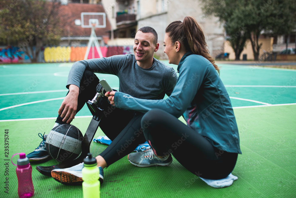 Naklejka premium Young man with prosthetic leg enjoying with his friend at basketball court.
