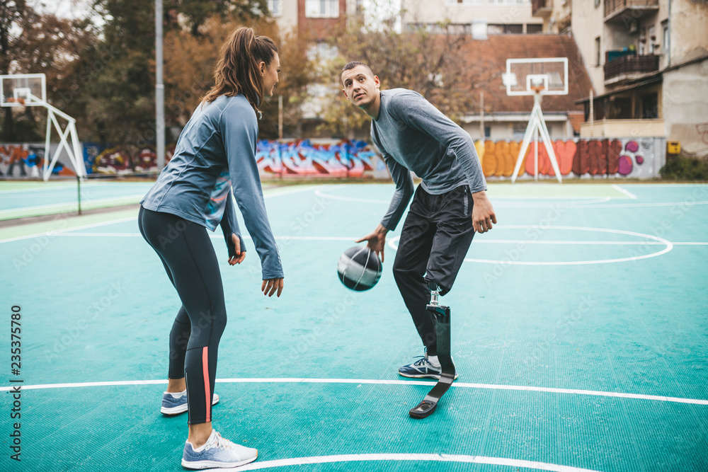 Fototapeta premium Young man with prosthetic leg playing basketball with his friend.