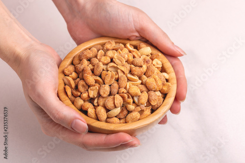Wooden bow of roasted peanuts in womans hands