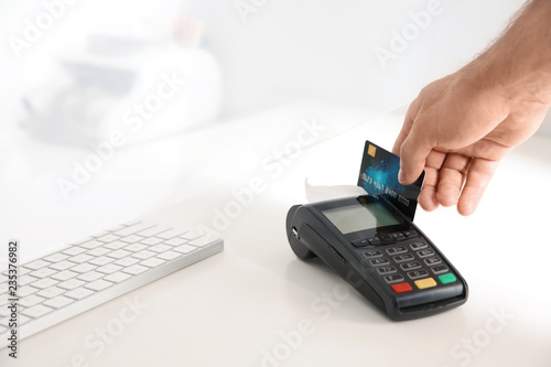 Man using bank terminal for credit card payment at cash department window, closeup