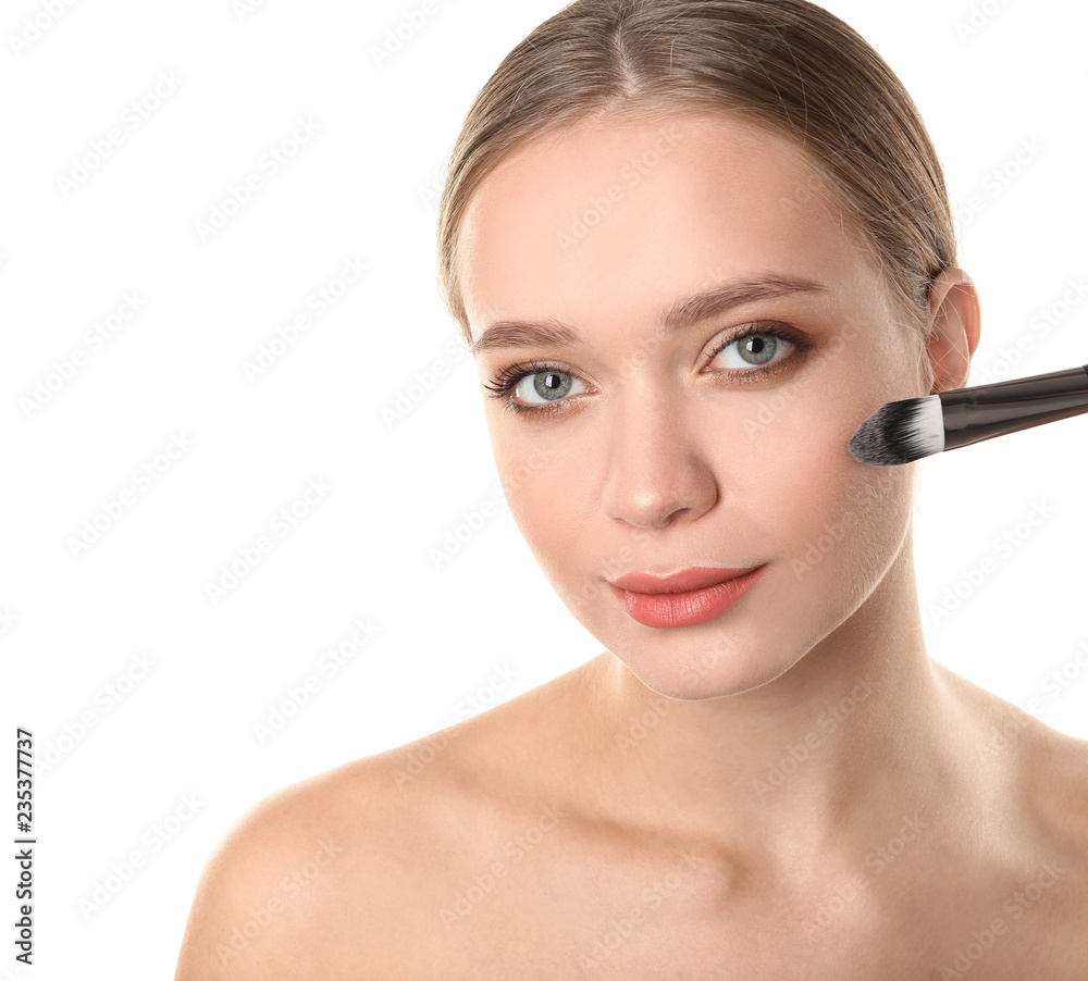 Portrait of beautiful young woman with makeup brush on white background