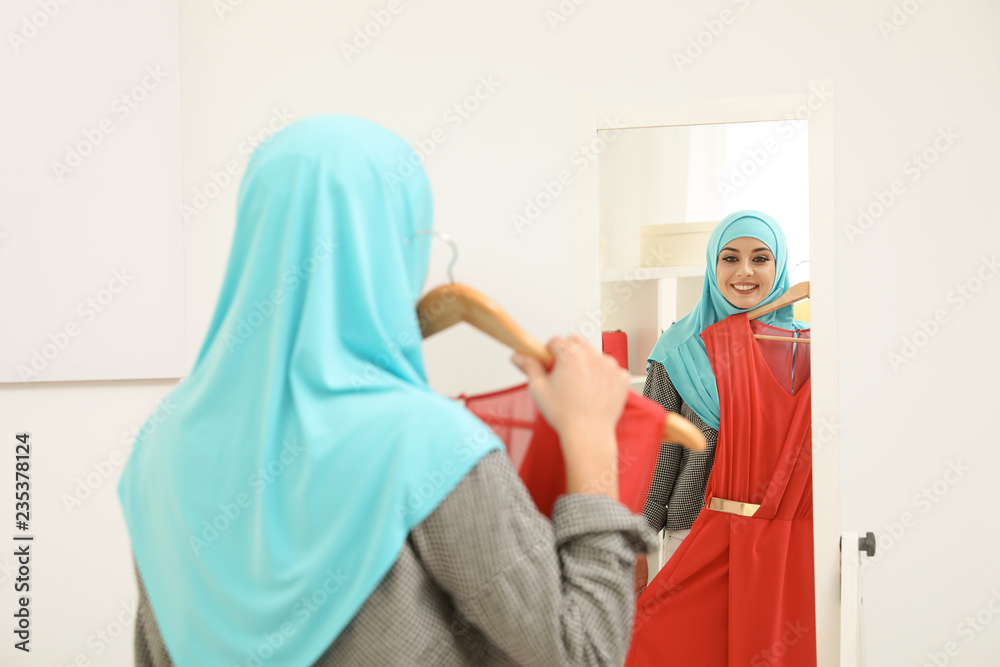 Muslim woman choosing clothes in modern shop
