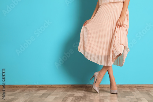 Young woman with beautiful long legs in stylish outfit near color wall, closeup. Space for text