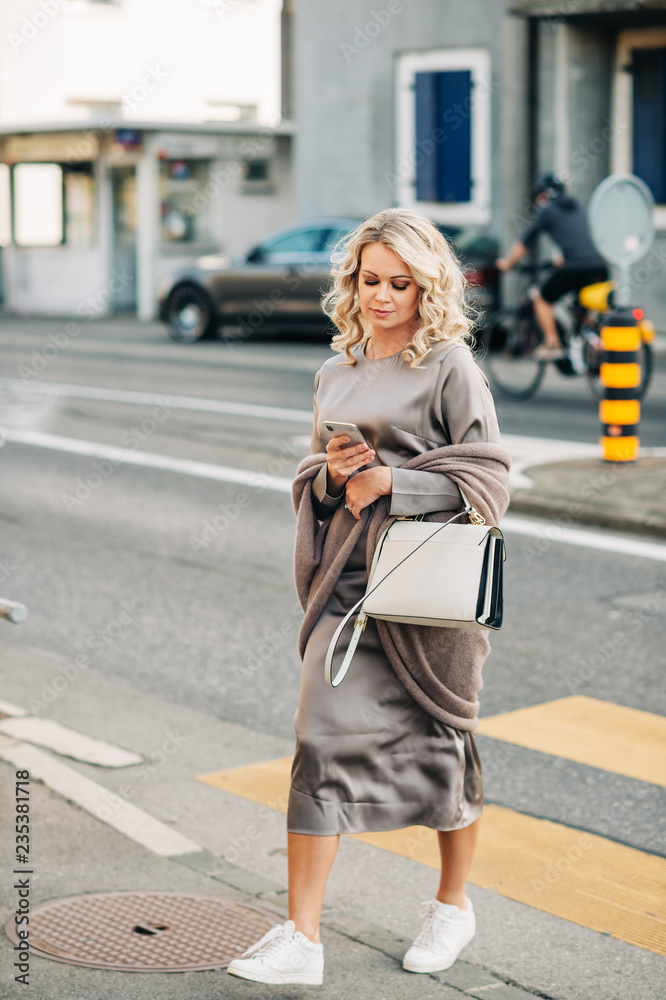 Beautiful woman crossing the road while using smartphone