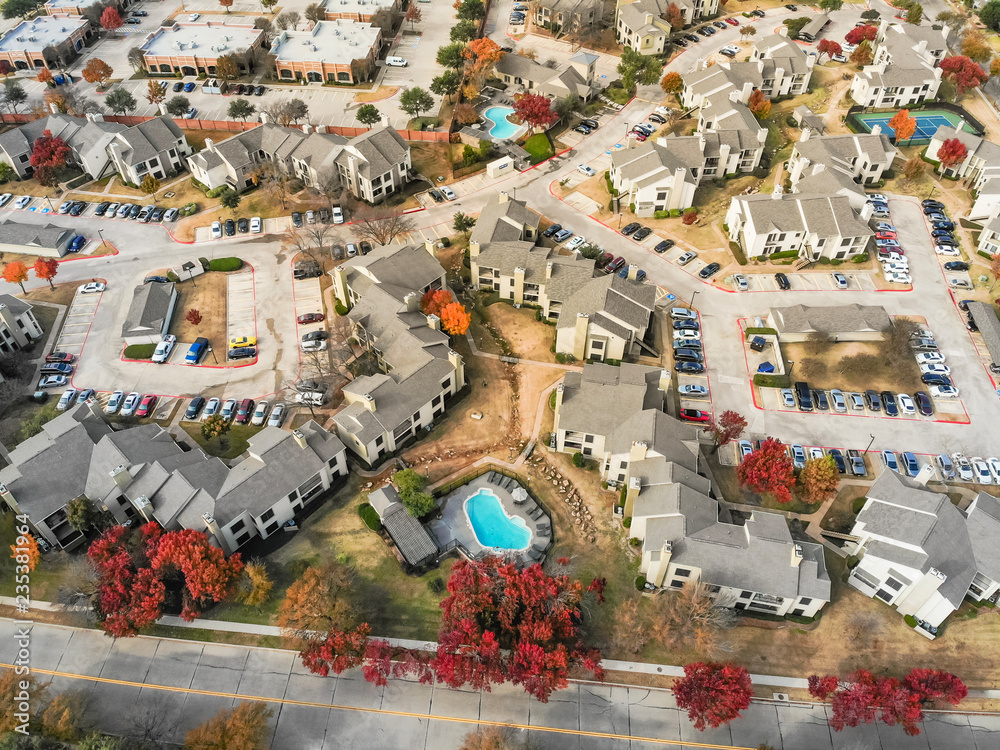 Top view apartment complex buildings with swimming pools in Valley Ranch suburb of Dallas, Texas, USA. Color full fall foliage surrounds row of multi-story flat units Top view apartment complex buildings with swimming pools in Valley Ranch suburb of Dallas, Texas, USA. Color full fall foliage surrounds row of multi-story flat units