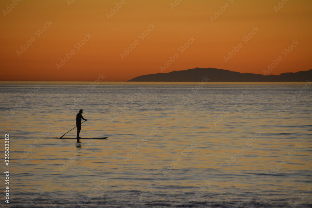 Paddle boarder on ocean at dusk