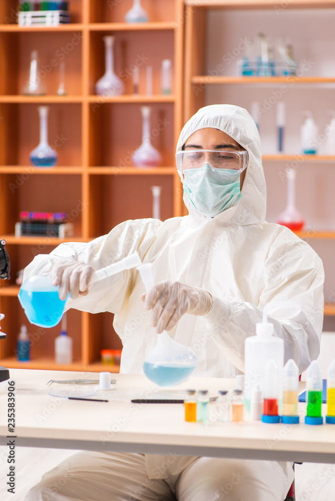 Young biochemist wearing protective suit working in the lab Young biochemist wearing protective suit working in the lab