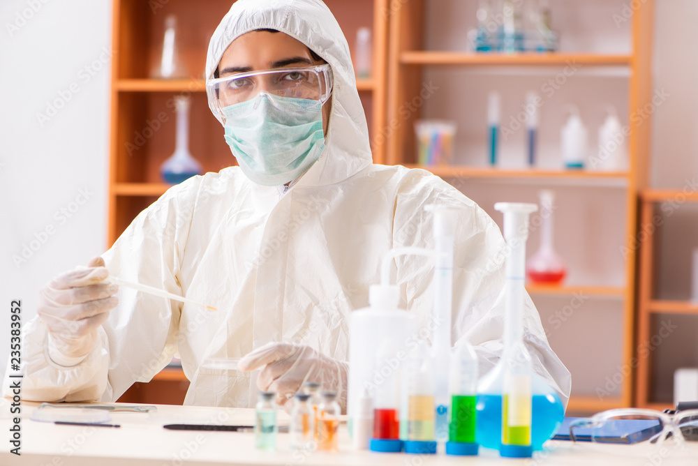 Young biochemist wearing protective suit working in the lab Young biochemist wearing protective suit working in the lab