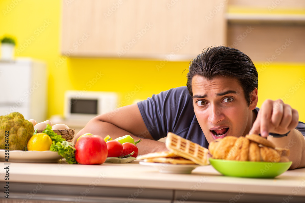 Man having hard choice between healthy and unhealthy food Man having hard choice between healthy and unhealthy food