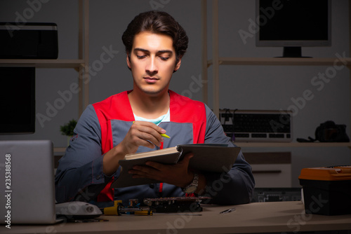 Young handsome repairman repairing computer 