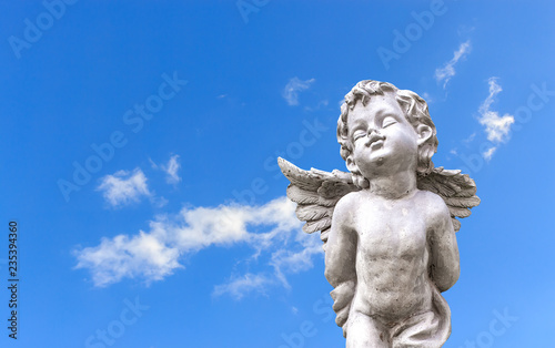 closeup cupid sculpture on blue sky with soft-focus and over light in the background