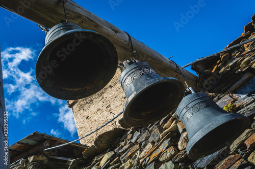 Bells in Lamaria church in Zhibiani - Ushguli community of villages, Upper Svaneti, Georgia, view from below with blue sky background photo