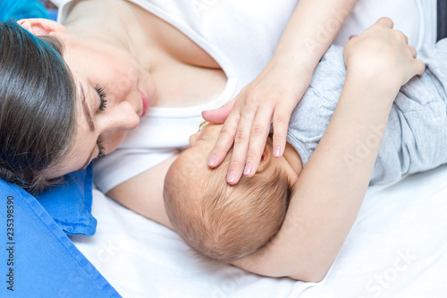 Young mother holding her newborn child. Mom nursing baby.