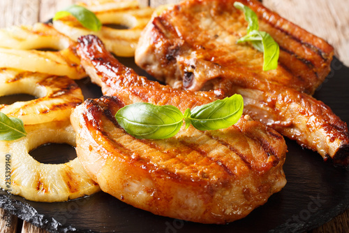 Grilled pork chop with pineapple and basil close-up on slate. horizontal