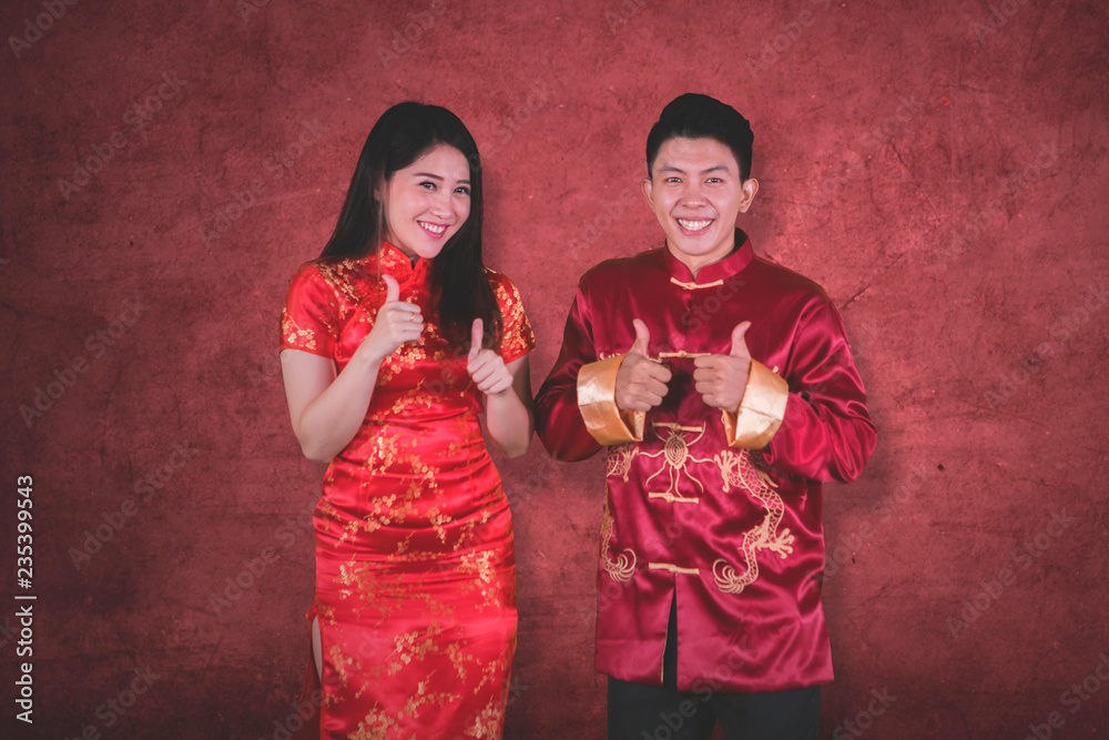 Obraz premium Asian couple shows thumbs up on studio
