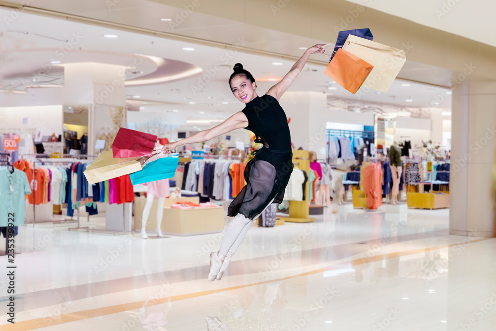 Ballerina leaping with shopping bags in the mall