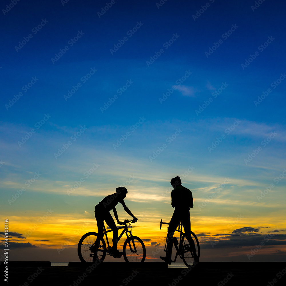Fototapeta premium Cyclists with bicycles at the beach, at dusk.