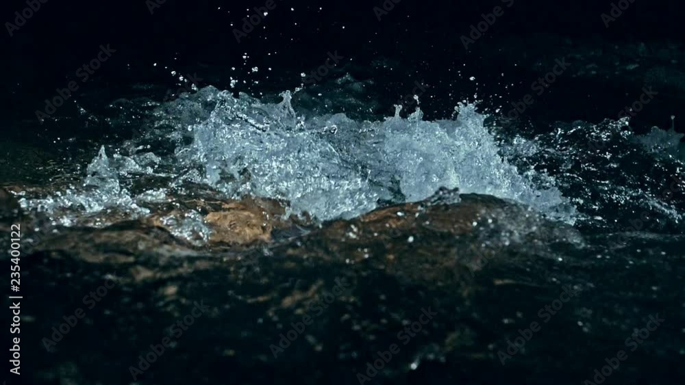 Slow motion of waves on dark water surface with play of flecks of bright light close up. Amazing dramatic natural background. Shooting with 180fps. Epic mystical and magic night view. Crystal clear