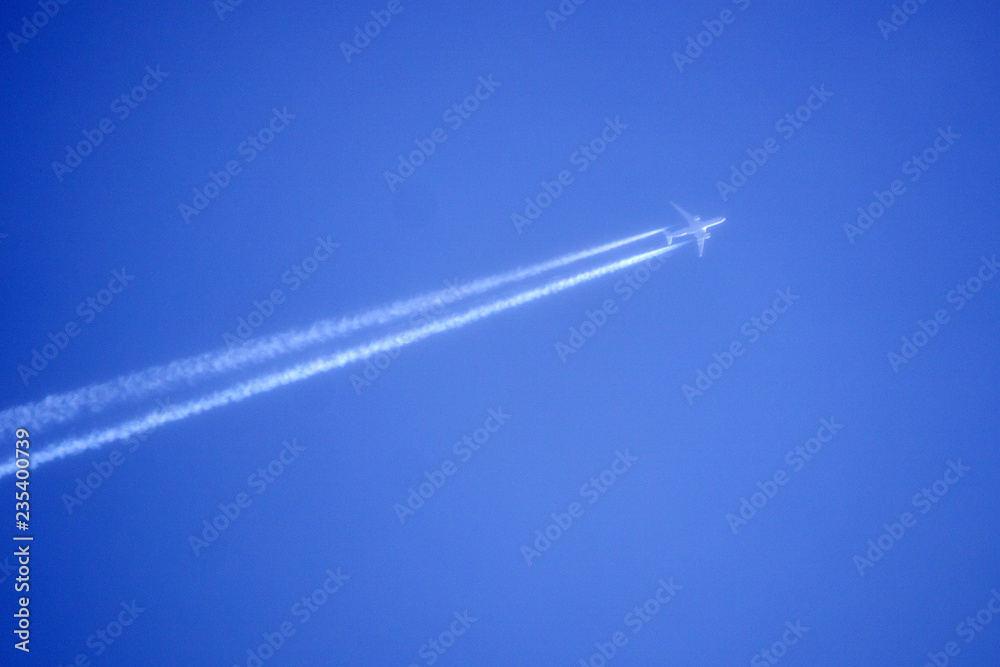 plane with condensation trail in front of blue sky . plane with condensation trail in front of blue sky .