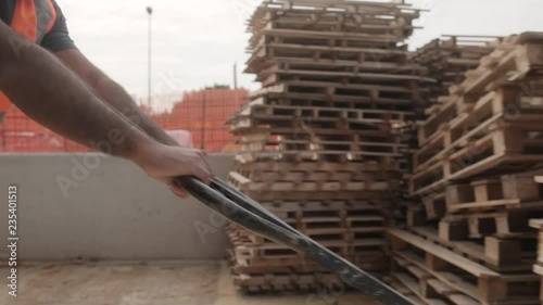 Skilled people working in construction site. Hispanic man at work in new house inside apartment building. Professional latino worker using manual pallet jack to move material. Close-up of hands photo