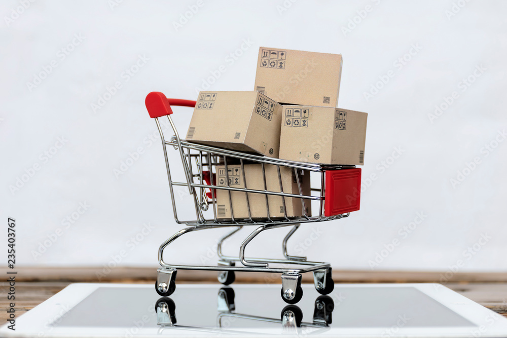 Online shopping,E-commerce and delivery service concept.Paper box stacked in Shopping cart on the tablet.