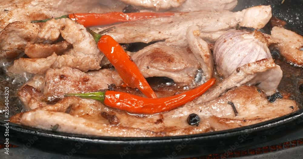 C4K closeup shot of the delicious pork bellies frying with peppers and herbs C4K closeup shot of the delicious pork bellies frying with peppers and herbs